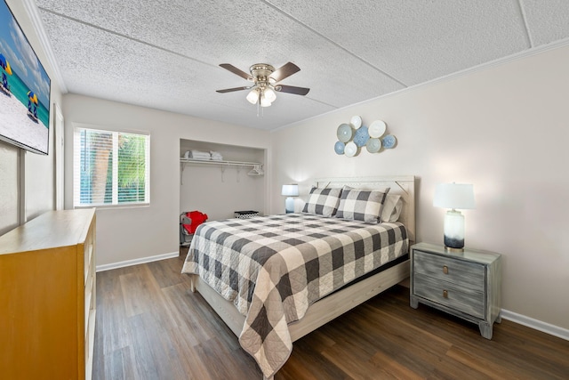 bedroom with a textured ceiling, a closet, ceiling fan, dark wood-type flooring, and ornamental molding