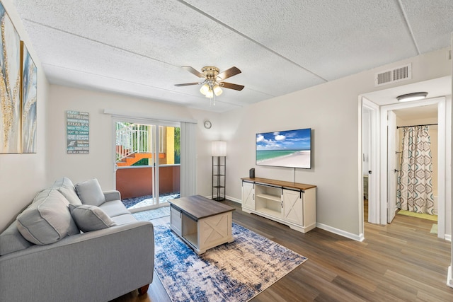 living room with ceiling fan, hardwood / wood-style flooring, and a textured ceiling