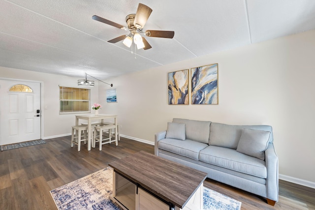 living room featuring dark wood-type flooring, a textured ceiling, and ceiling fan