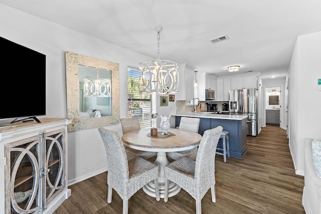 dining space featuring sink, an inviting chandelier, and dark hardwood / wood-style floors