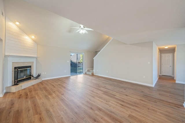 unfurnished living room with ceiling fan, lofted ceiling, light hardwood / wood-style flooring, and a tiled fireplace