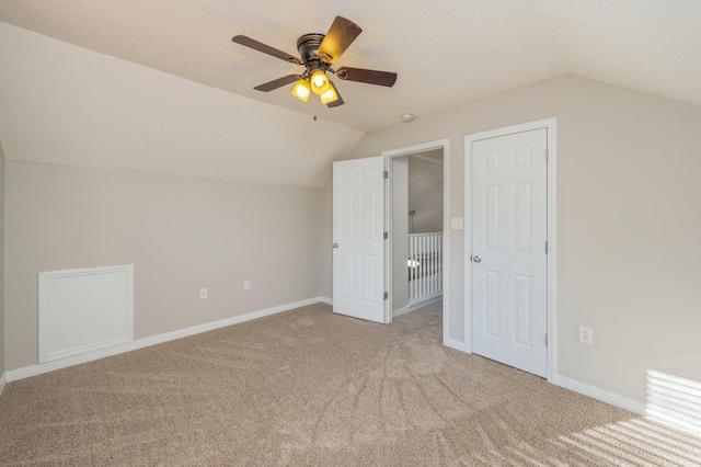 additional living space with a textured ceiling, ceiling fan, light carpet, and vaulted ceiling