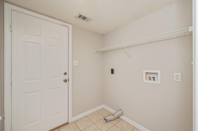 clothes washing area featuring electric dryer hookup, light tile patterned flooring, washer hookup, and a textured ceiling