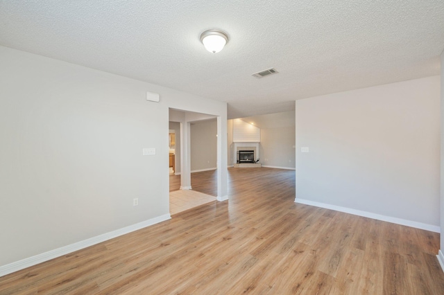 unfurnished room with a textured ceiling and light hardwood / wood-style flooring