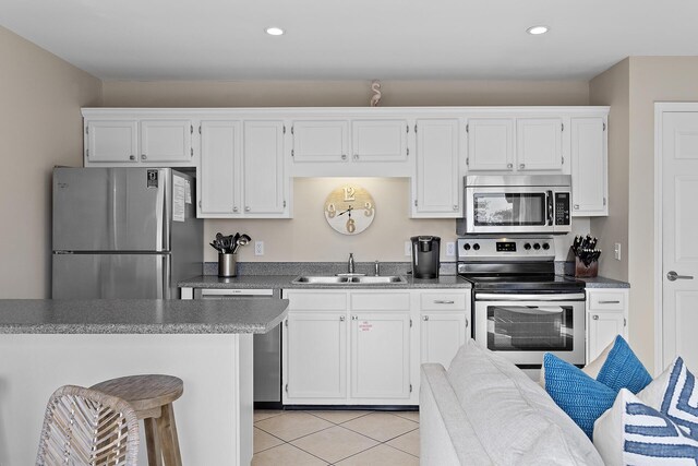 kitchen with sink, white cabinets, light tile patterned floors, and appliances with stainless steel finishes