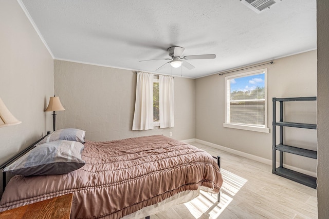 bedroom featuring a textured ceiling, multiple windows, light wood-type flooring, and ceiling fan