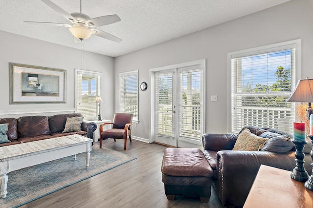 living room featuring ceiling fan, a textured ceiling, light hardwood / wood-style floors, and plenty of natural light