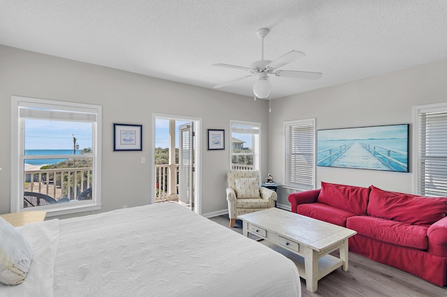 bedroom featuring a water view, ceiling fan, a textured ceiling, and light hardwood / wood-style flooring