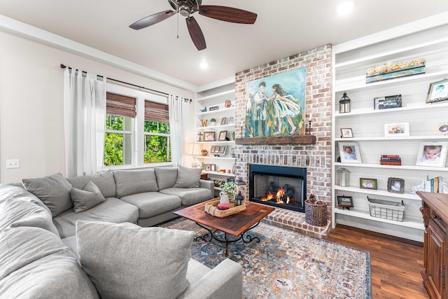 living room featuring ceiling fan, built in features, dark hardwood / wood-style flooring, and a brick fireplace