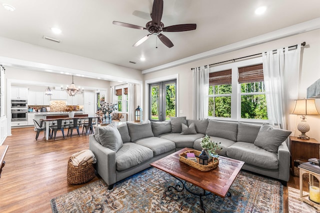 living room featuring light hardwood / wood-style floors and ceiling fan with notable chandelier