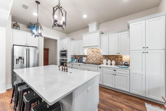 kitchen featuring white cabinetry, decorative light fixtures, decorative backsplash, dark hardwood / wood-style floors, and a kitchen island with sink