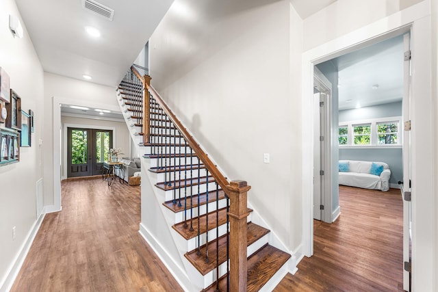 stairway featuring french doors and wood-type flooring