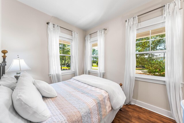 bedroom with multiple windows and dark hardwood / wood-style flooring