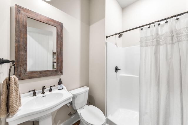 bathroom with toilet, sink, and a shower with shower curtain