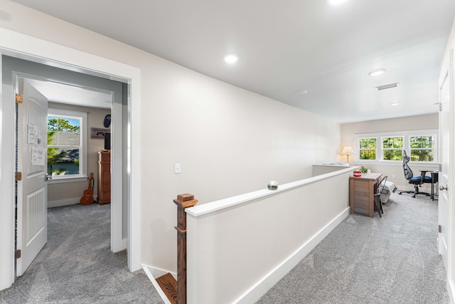 corridor with a healthy amount of sunlight and carpet flooring