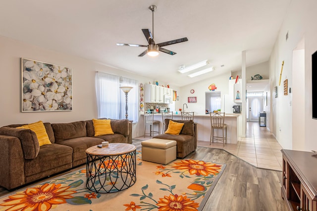 living room featuring sink, vaulted ceiling, light hardwood / wood-style flooring, and ceiling fan