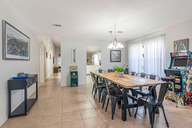 tiled dining area with a textured ceiling, a chandelier, and plenty of natural light