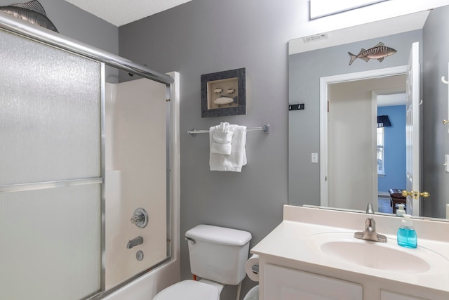 full bathroom featuring vanity, toilet, a textured ceiling, and shower / bath combination with glass door