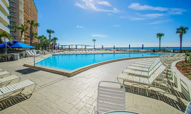 view of swimming pool featuring a patio and a water view