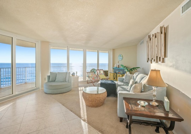 living room with plenty of natural light, a water view, light tile patterned floors, and a textured ceiling