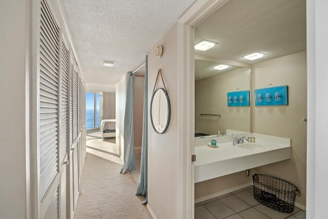 bathroom with a textured ceiling, a water view, and sink