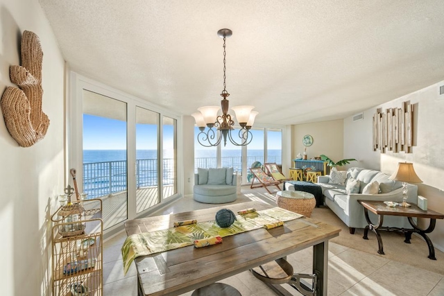 tiled dining space with a water view, a healthy amount of sunlight, a textured ceiling, and a notable chandelier