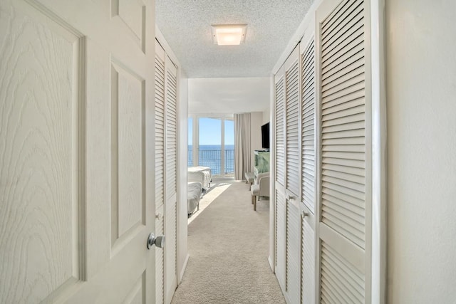 hallway with light carpet and a textured ceiling