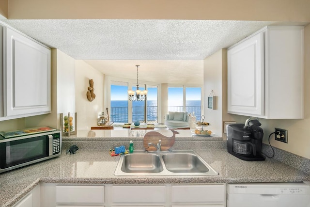 kitchen featuring white dishwasher, an inviting chandelier, white cabinetry, and a water view