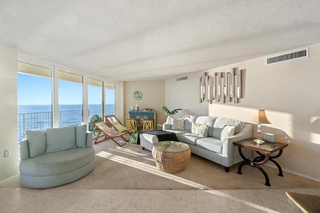 tiled living room with a textured ceiling and a water view