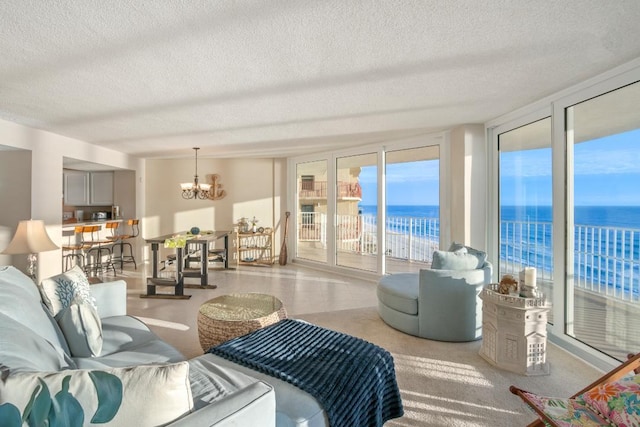 sunroom featuring a beach view, a water view, and a notable chandelier