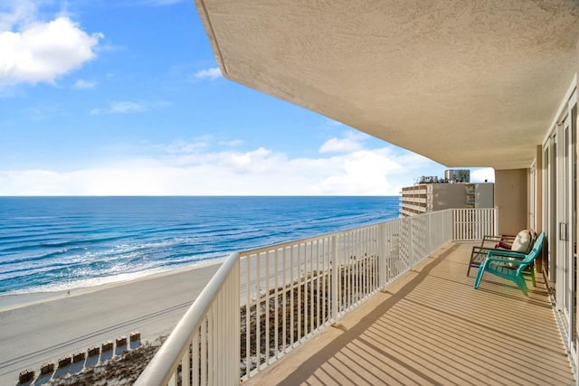 balcony featuring a water view and a beach view