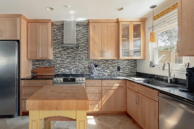 kitchen featuring wall chimney range hood, light brown cabinetry, appliances with stainless steel finishes, butcher block countertops, and hanging light fixtures