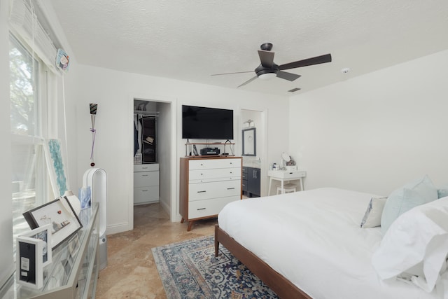 bedroom featuring a closet, ceiling fan, a textured ceiling, and a walk in closet