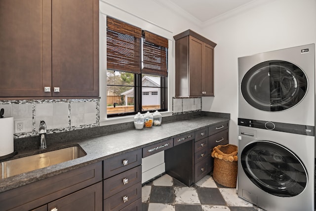 laundry room with cabinets, stacked washer / dryer, ornamental molding, and sink