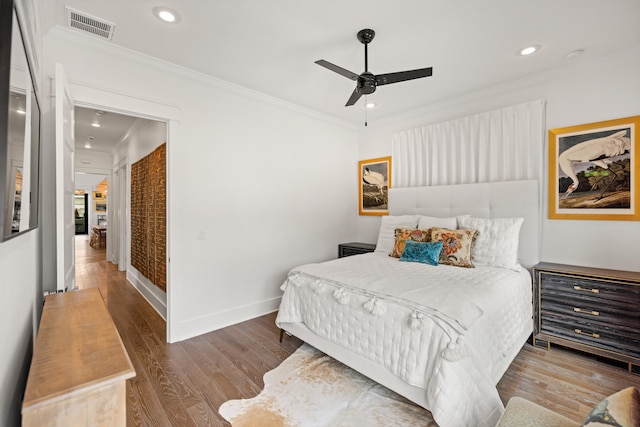 bedroom with ceiling fan, crown molding, and wood-type flooring