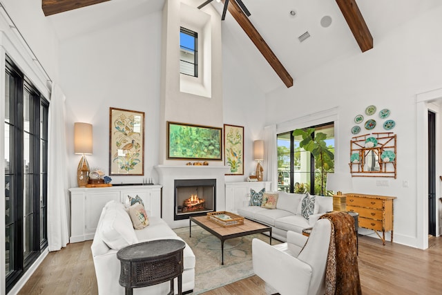 living room featuring beamed ceiling, light hardwood / wood-style floors, and high vaulted ceiling