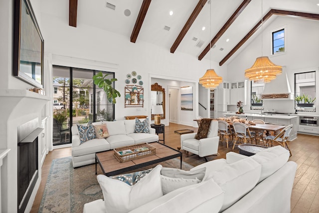 living room with beamed ceiling, high vaulted ceiling, wood-type flooring, and a notable chandelier