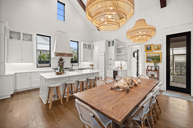 dining area featuring a notable chandelier, beverage cooler, dark wood-type flooring, and high vaulted ceiling