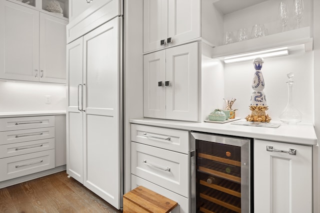 bar with hardwood / wood-style floors, white cabinetry, and beverage cooler