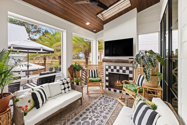 sunroom with wood ceiling, exterior fireplace, a healthy amount of sunlight, and vaulted ceiling