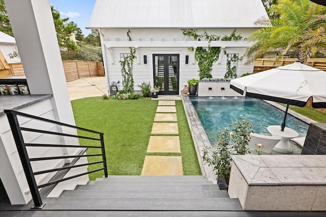 back of house featuring a lawn, a patio, and french doors