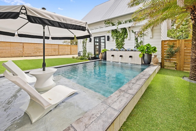 view of swimming pool with a lawn and french doors