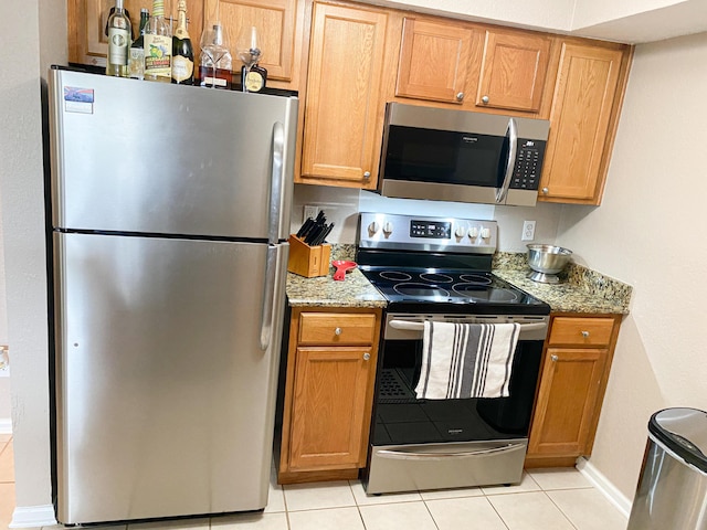 kitchen featuring light stone counters, stainless steel appliances, and light tile patterned flooring