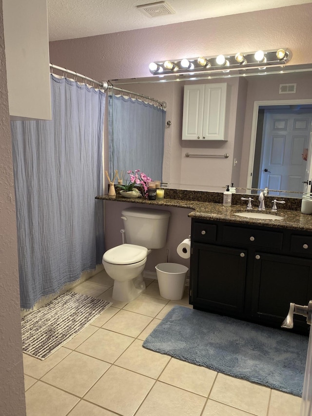 bathroom with toilet, a textured wall, vanity, and tile patterned floors