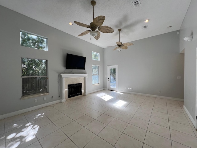 unfurnished living room featuring a tile fireplace, light tile patterned floors, a textured ceiling, and high vaulted ceiling