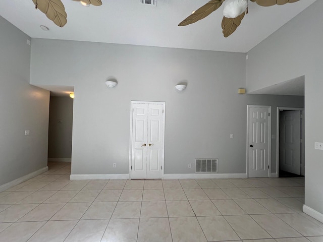 empty room with high vaulted ceiling, a ceiling fan, light tile patterned flooring, and visible vents