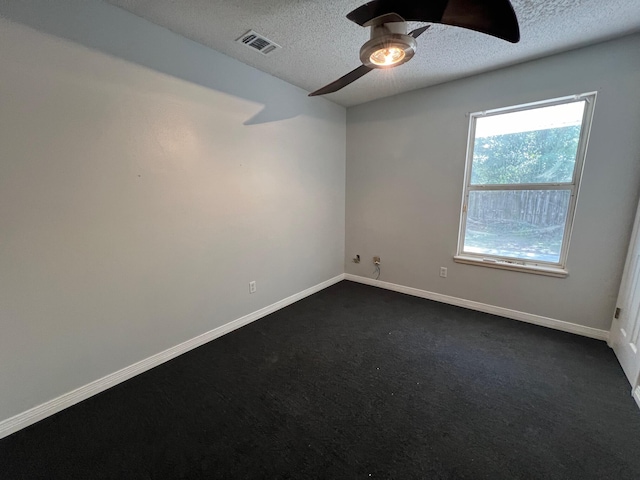 spare room with dark colored carpet, ceiling fan, and a textured ceiling