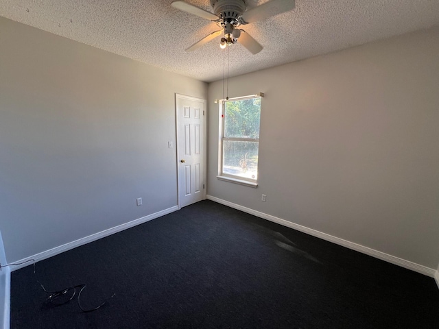 empty room featuring baseboards, ceiling fan, dark colored carpet, and a textured ceiling