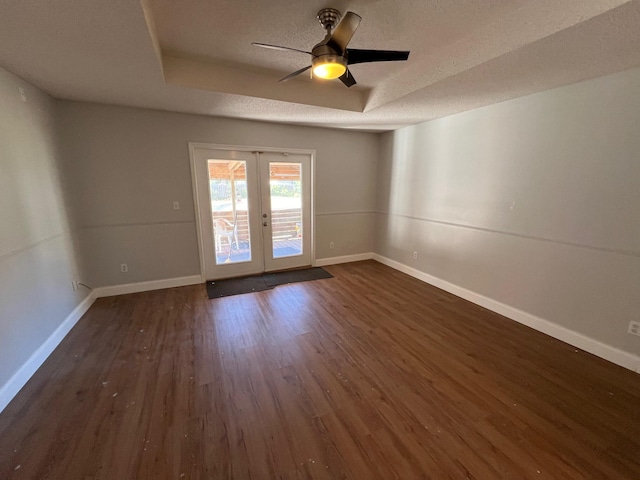 spare room with dark wood-style flooring, baseboards, ceiling fan, a raised ceiling, and french doors