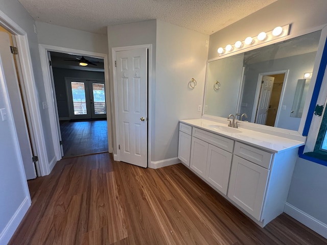 bathroom with baseboards, a textured ceiling, french doors, and wood finished floors